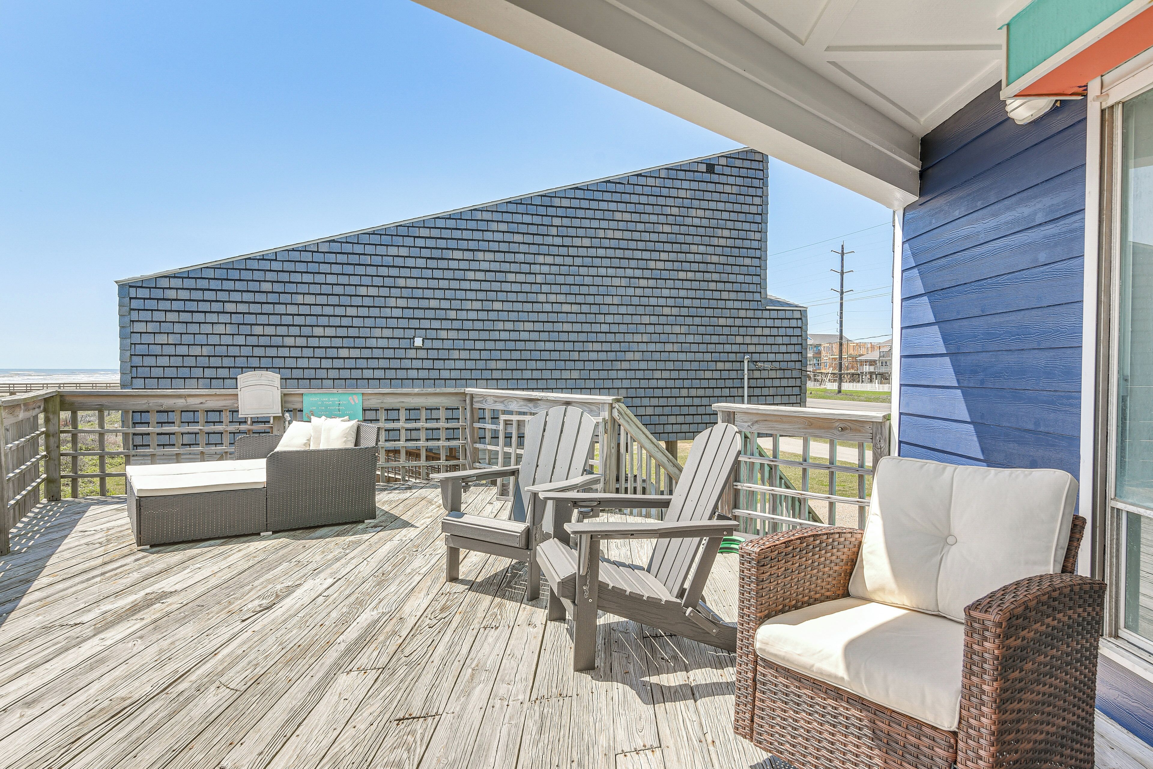 A wooden deck with wicker furniture and a view of a modern building.