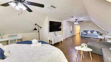 Quarto com cama, escrivaninha, televisão e ventilador de teto.