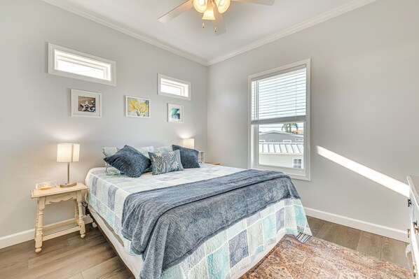 A bedroom with a bed, bedside table, lamp, and artwork on the wall. - 1 Mi to Beach Access: Home w/ Porch in Fort Myers! (Fort Myers)