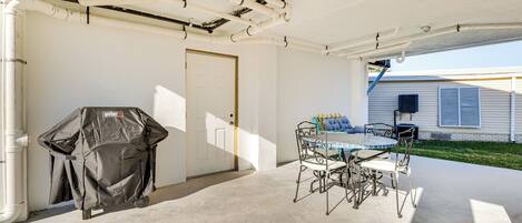 Un patio couvert comprenant un barbecue, une table et des chaises.