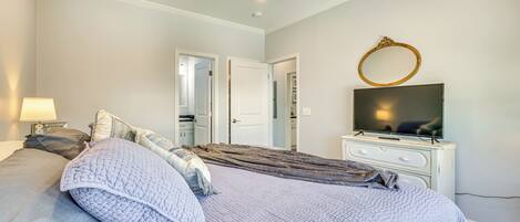 A bedroom with a bed, a TV, a ceiling fan, and a dresser.