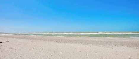 Uma praia com céu claro e mar calmo.
