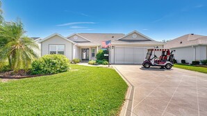 A residential house with a well-maintained lawn, a driveway, and a golf cart parked in front. - 2 Mi to Lake Sumter Landing: Spacious Golf Retreat (The Villages)