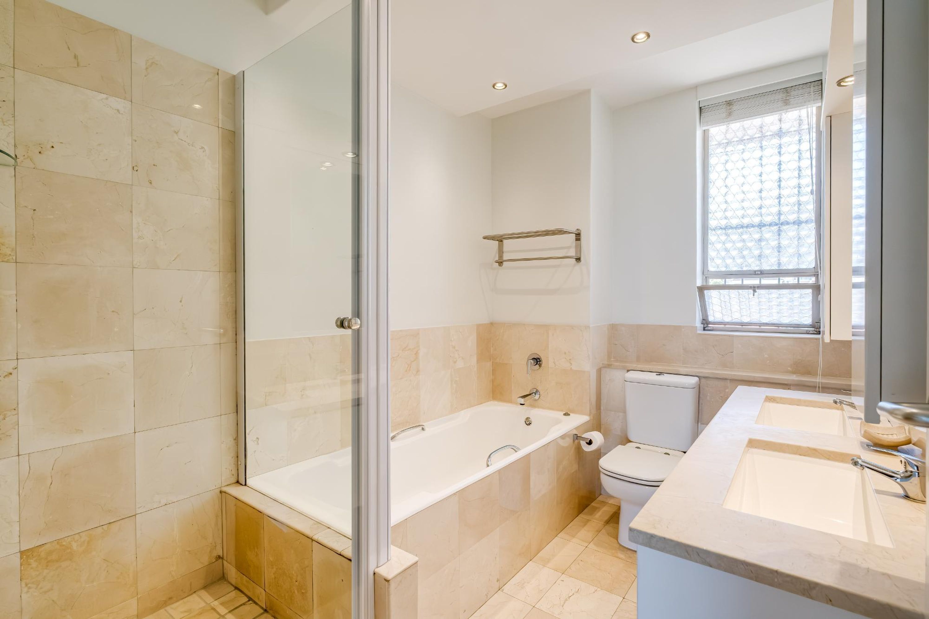 A modern bathroom with a glass-enclosed shower, a freestanding bathtub, a toilet, and a vanity with two sinks.