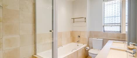 A modern bathroom with a glass-enclosed shower, a freestanding bathtub, a toilet, and a vanity with two sinks.
