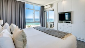 A modern hotel room with a large bed, a TV, and a view of the ocean. - Camps Bay Beachside 2bed w Sea View Cloud 9 (Cape Town)