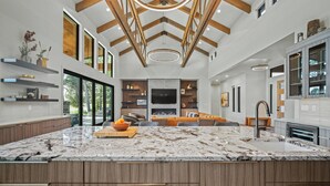 A spacious kitchen with a large island, wooden beams, and built-in shelving.