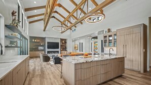 A spacious kitchen with wooden cabinets, a large island, and a modern pendant light.