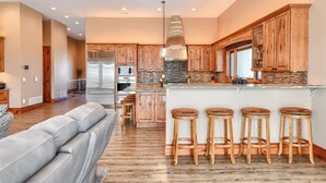 A modern kitchen with wooden cabinets, a central island with stools, and a built-in oven. - Incredible Panoramic View, Close to Spearfish, Very Open Floor Plan & Paved! (Spearfish)