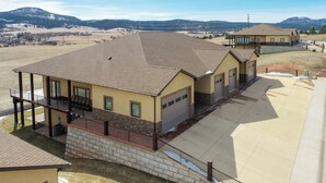 A residential building with a flat roof, a garage, and a balcony with outdoor furniture. - Incredible Panoramic View, Close to Spearfish, Very Open Floor Plan & Paved! (Spearfish)