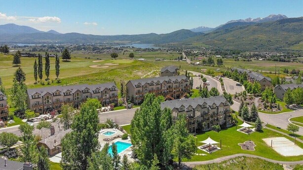Un resort con varias edificaciones, una piscina y un campo de golf al fondo.