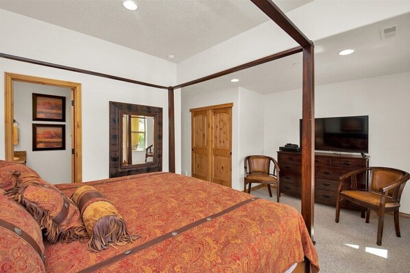 A bedroom with a four-poster bed, wooden wardrobe, television, and two chairs. - MH1208 | Alpine Nest Retreat: Adventure Awaits in Eden, UT! (Eden)