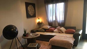 A cozy bedroom with a bed, a side table, a lamp, a chair, and a small table. - Nice house in the center of Arès (Unknown)