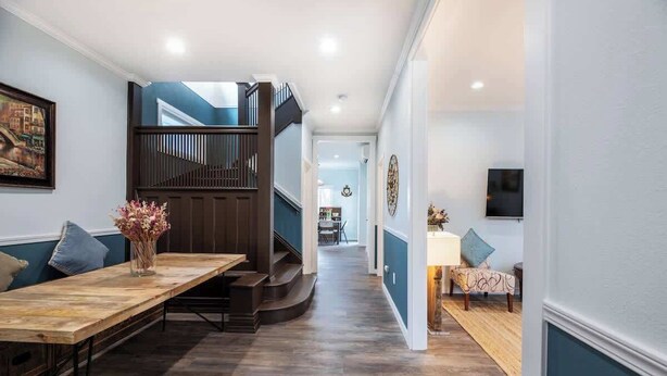 Un intérieur moderne avec une table à manger en bois, un escalier et un coin salon agrémenté de coussins.