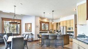 Una cocina moderna con una isla central, taburetes de bar y un comedor con mesa y sillas.