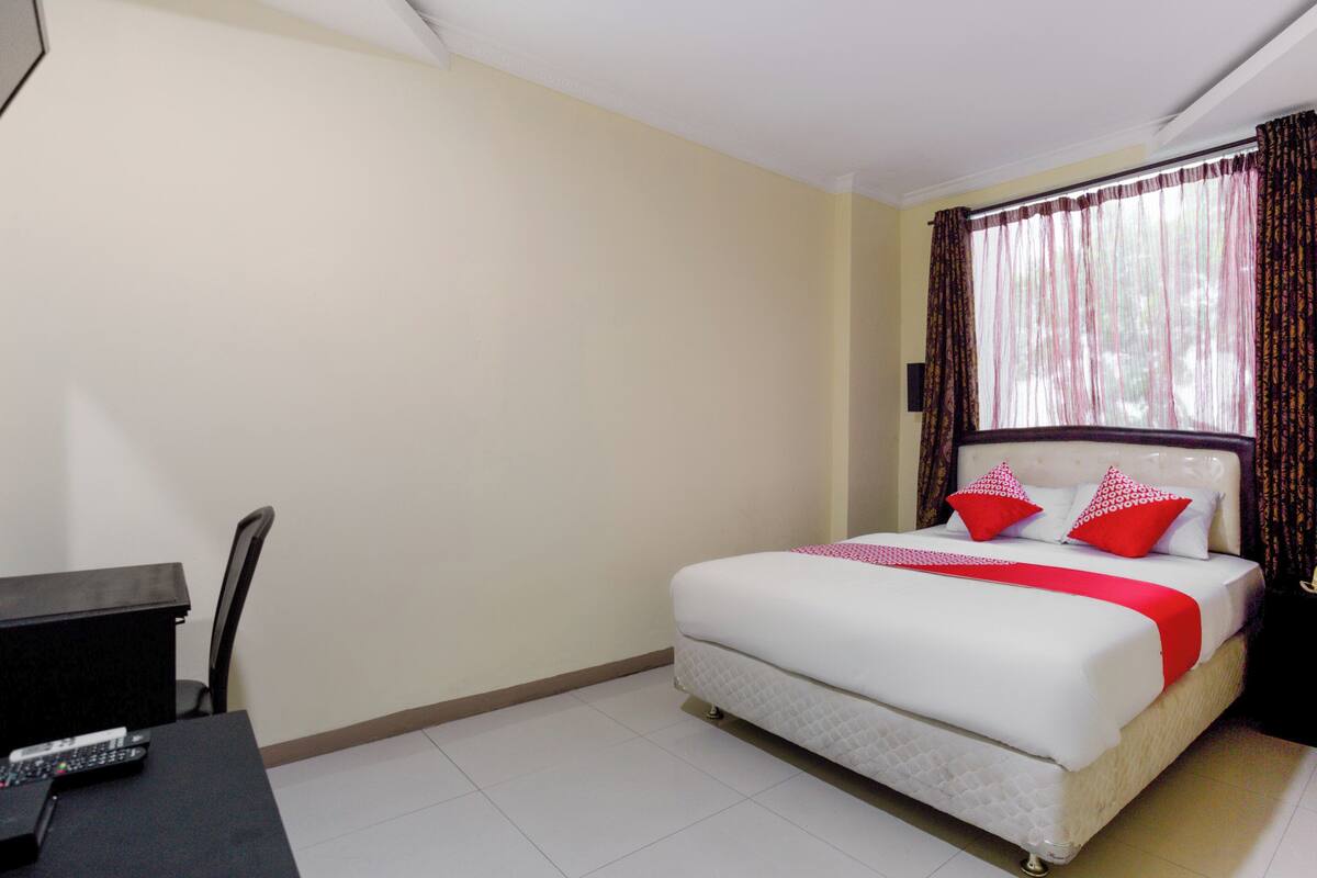 A hotel room with a bed, a desk, and a chair.