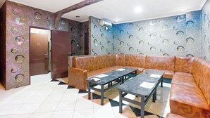 A lobby with a brown leather sofa, two tables, patterned walls, and a door marked "10". - Hotel O Bekasi Near Mall Lippo Cikarang Formerly Hotel Addictk (Cikarang)
