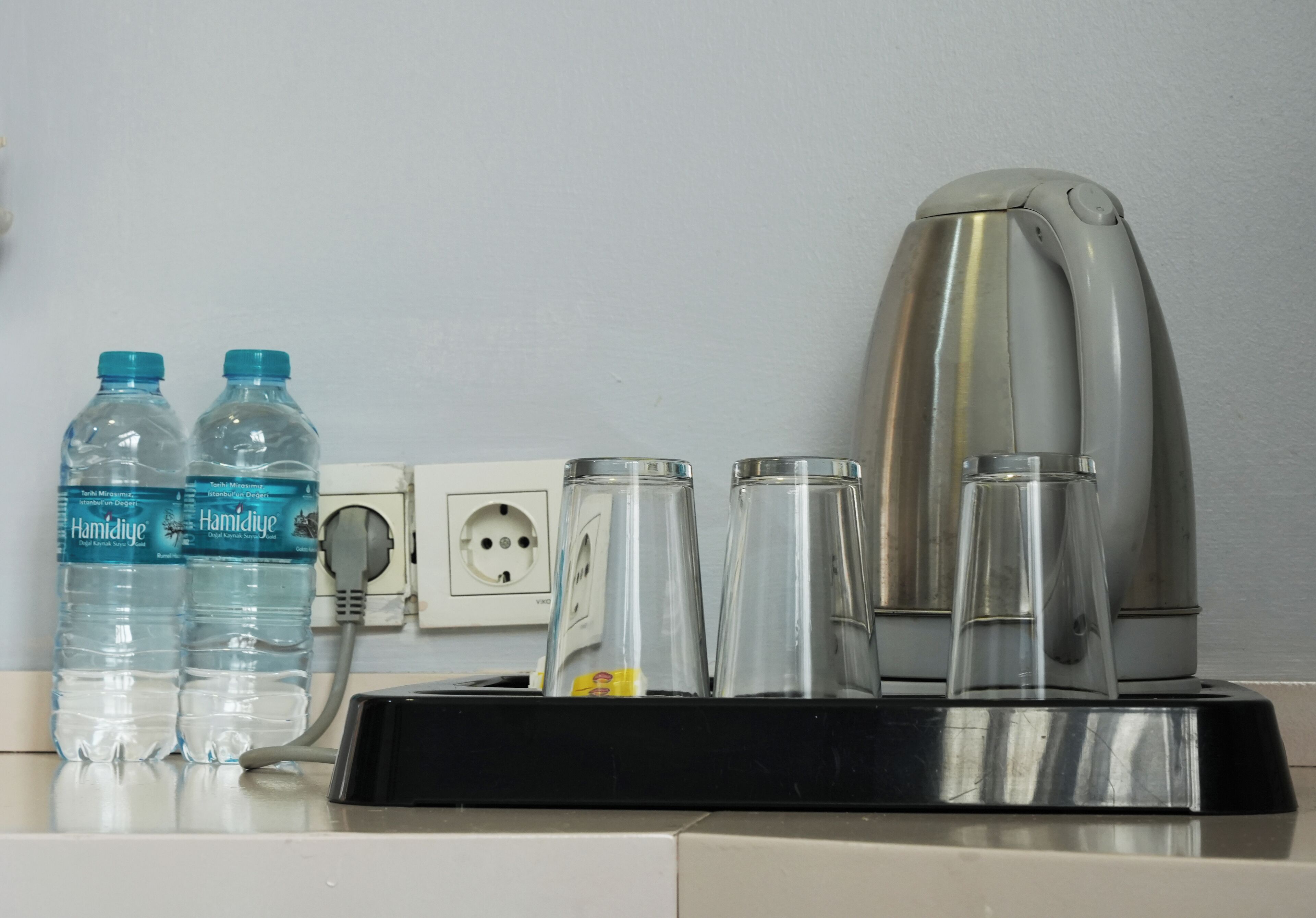 Un piano di lavoro in cucina con due bottiglie d'acqua, una macchina da caffè e un bollitore.