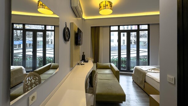 Een moderne hotelkamer met een slaapbank, een bureau en een grote spiegel.