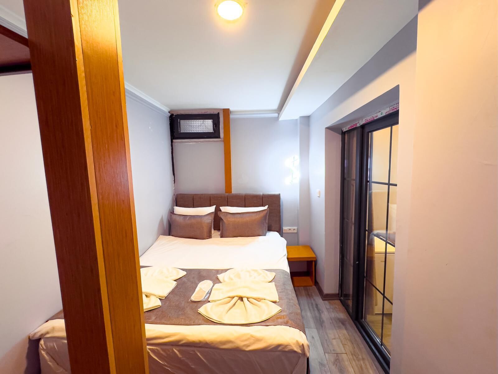 Une chambre d’hôtel avec un lit, une table de chevet, une fenêtre et une porte.