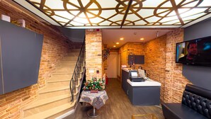 Een modern interieur met een trap, een receptiebalie, een bank en een televisie.