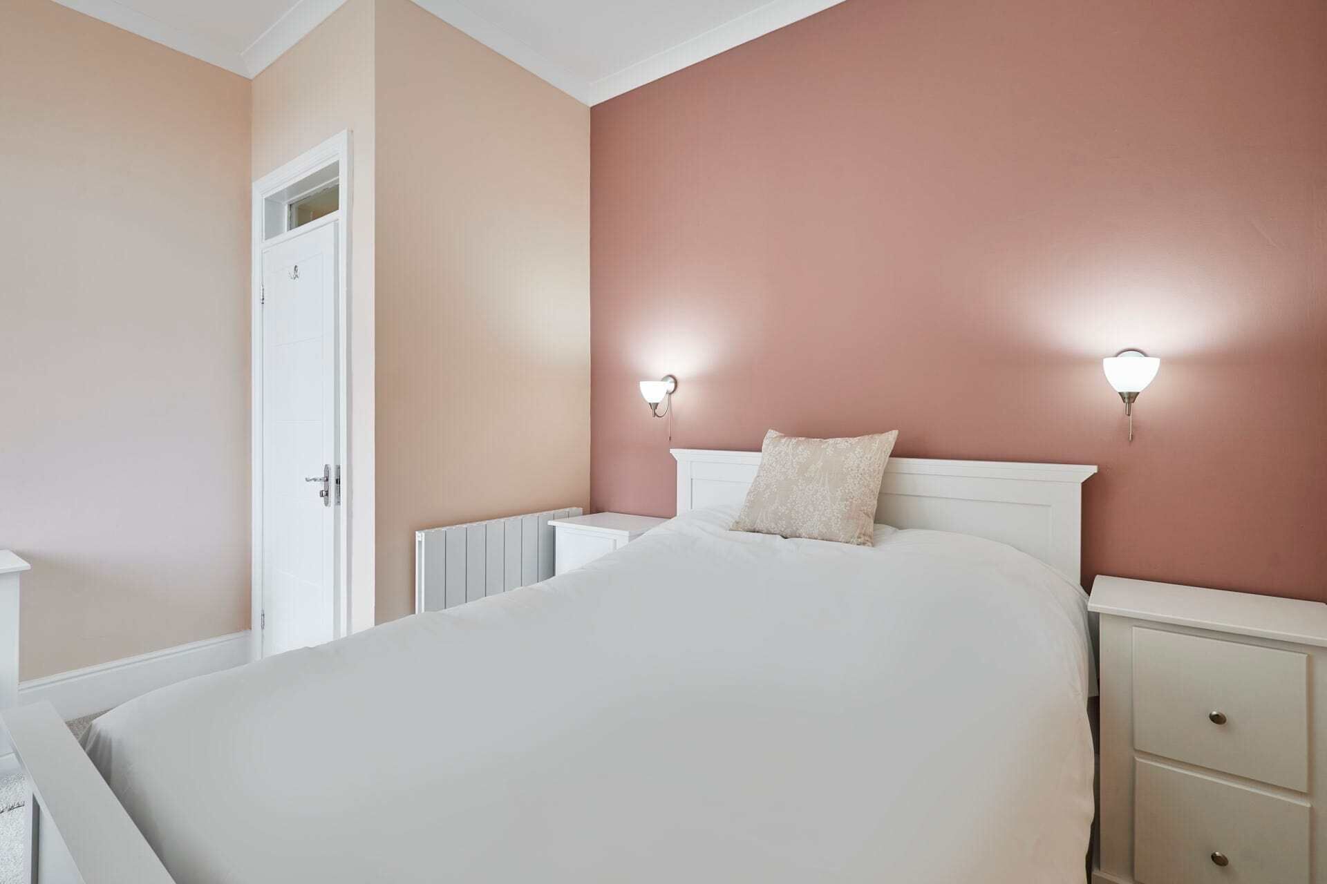 A bedroom with a bed, bedside tables, and a radiator.