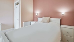 A bedroom with a bed, bedside tables, and a radiator.