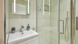 A modern bathroom with a glass-enclosed shower, a white sink, and a mirror above the sink.
