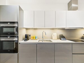 A modern kitchen with stainless steel appliances, a sink, and a knife block. - Stylish & Designer Camden Town Apartment (Greater London)