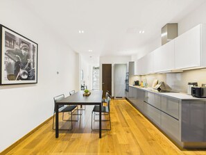 A modern kitchen with a central island, built-in appliances, and a dining area with a long table and benches.