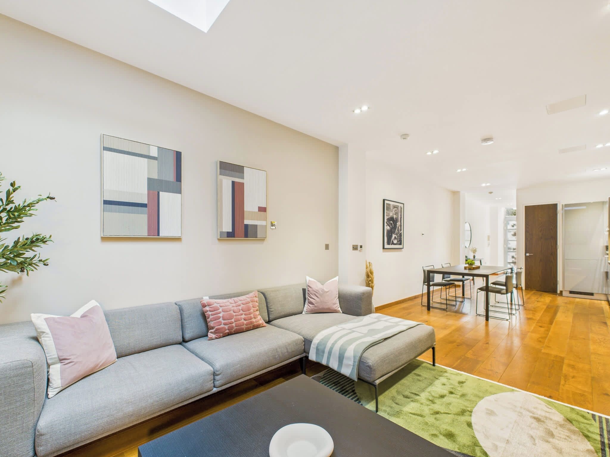 A modern living room with a grey sectional sofa, a coffee table, and a dining area with a table and chairs.