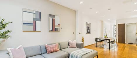A modern living room with a grey sectional sofa, a coffee table, and a dining area with a table and chairs.