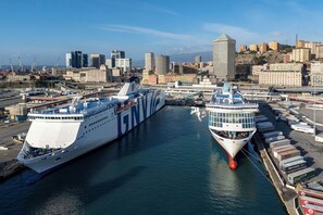 A large cruise ship docked at a port with a cityscape in the background. - Pleasant 2BR flat next to Genoa Port (Genoa)