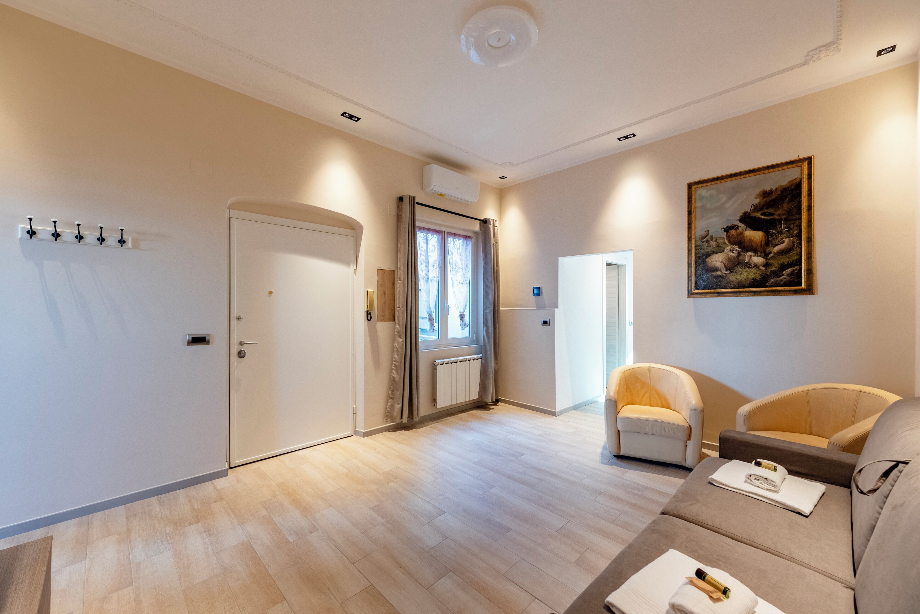 A modern living room with a sofa, a chair, a painting, and a door with a coat rack.