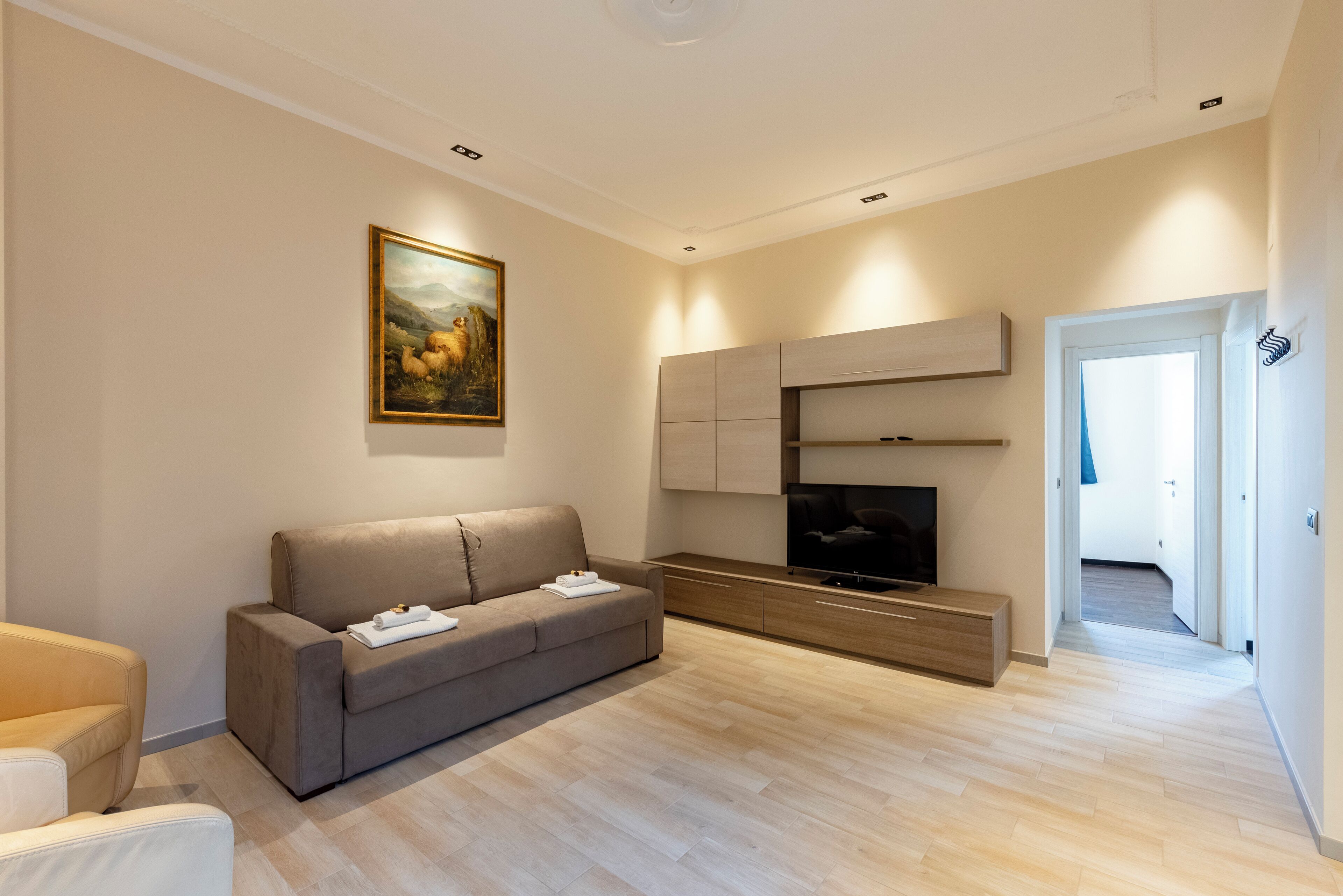 A modern living room with a sofa, TV, and artwork on the wall.