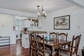 Un coin repas avec une table et des chaises en bois, un lustre et un tableau encadré au mur.