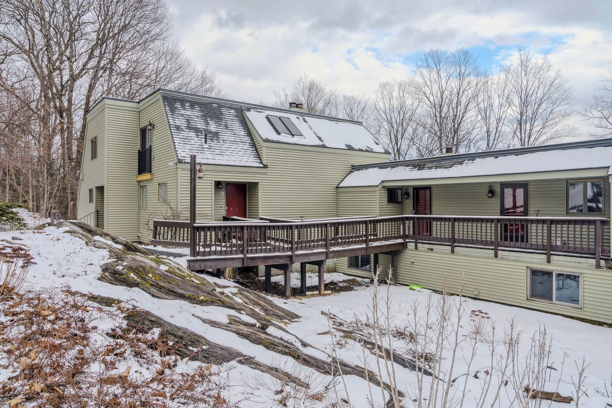 A two-story house with a covered porch and a small deck.