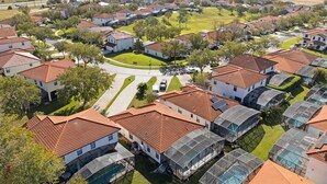 A residential area with houses featuring red-tiled roofs and green lawns.