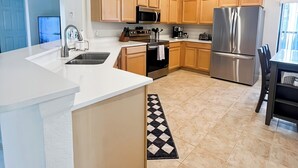 A modern kitchen with a central island, stainless steel appliances, and light wood cabinetry.