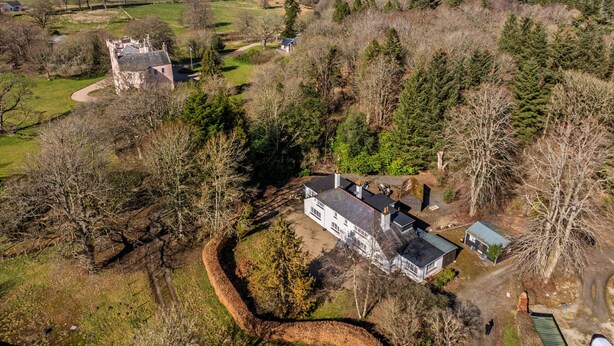 Una vista aerea di una tenuta rurale con una casa principale, un edificio più piccolo e una struttura simile a un castello.