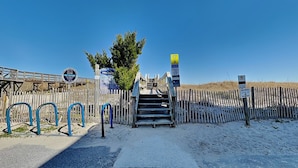 A beach entrance with a wooden fence, a staircase, and a parking sign.