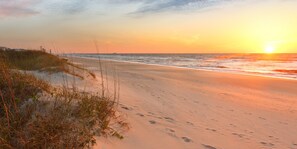 Ein Strand mit Dünen und einem Sonnenuntergang.