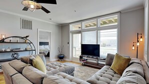 A modern living room with a large sectional sofa, a flat-screen TV, and a dining area with a table and chairs.
