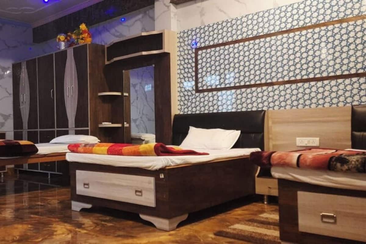 Habitación de hotel con cama, escritorio, silla, armario y espejo.