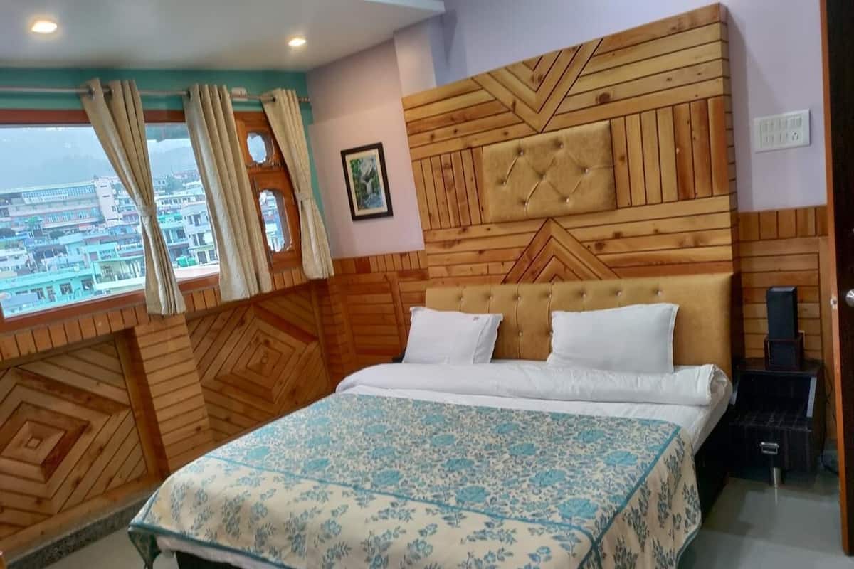 Un dormitorio con cabecera de madera, cama con ropa de cama blanca, ventana con cortinas y vista a la ciudad.