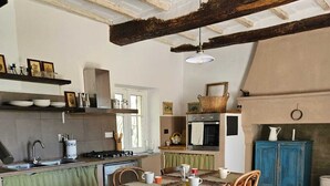 Une cuisine rustique avec une table en bois, des chaises et un luminaire suspendu.