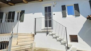 Un bâtiment à deux étages doté d’un balcon à l’étage supérieur, d’un escalier menant à l’entrée et d’un petit jardin à l’avant.