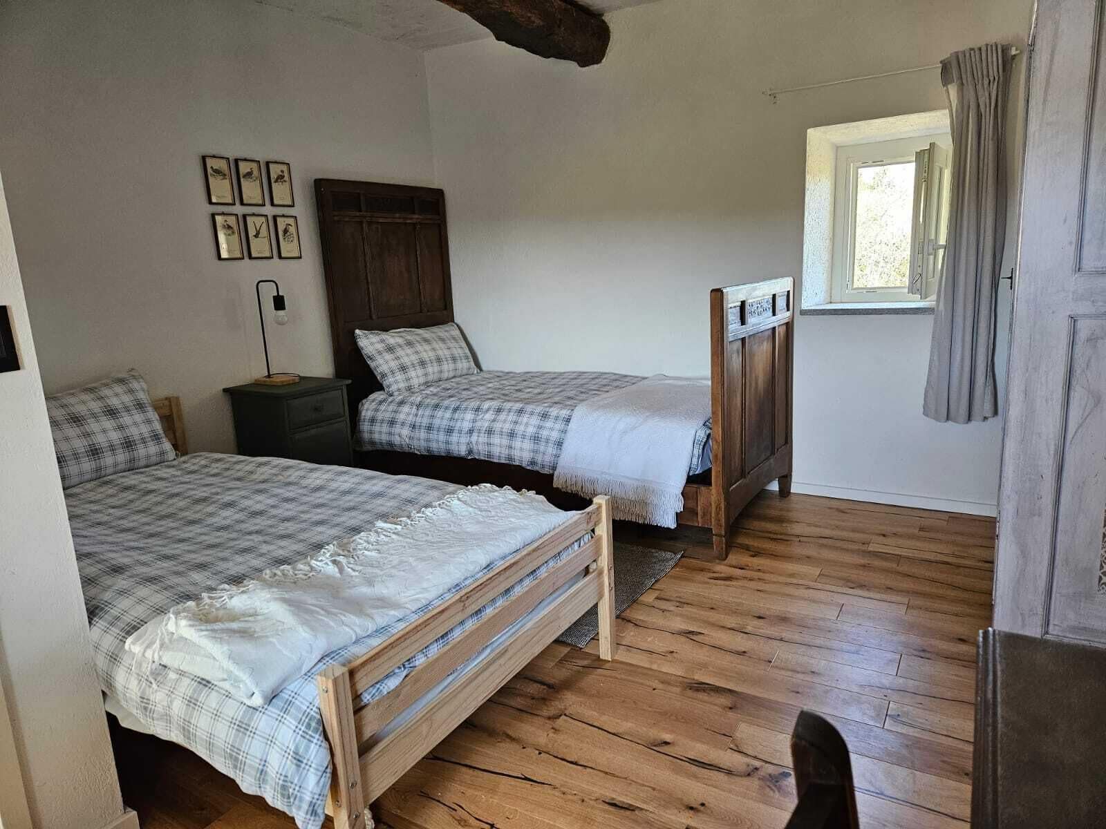 Ein Schlafzimmer mit zwei Holzbett, einem Nachttisch, einem Holzschrank und einem Fenster mit Vorhängen.