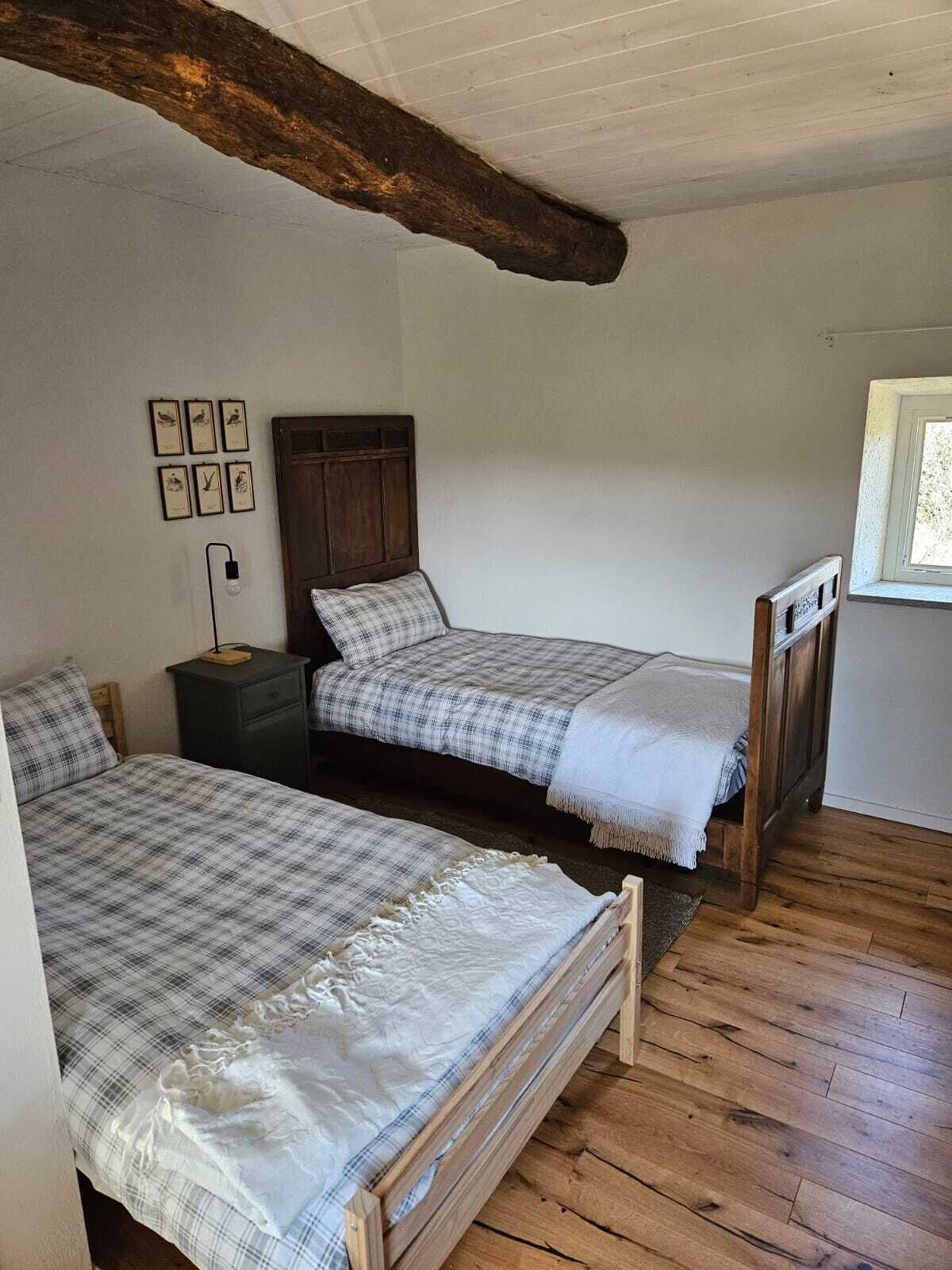 A room with two wooden beds, a nightstand, and a window.
