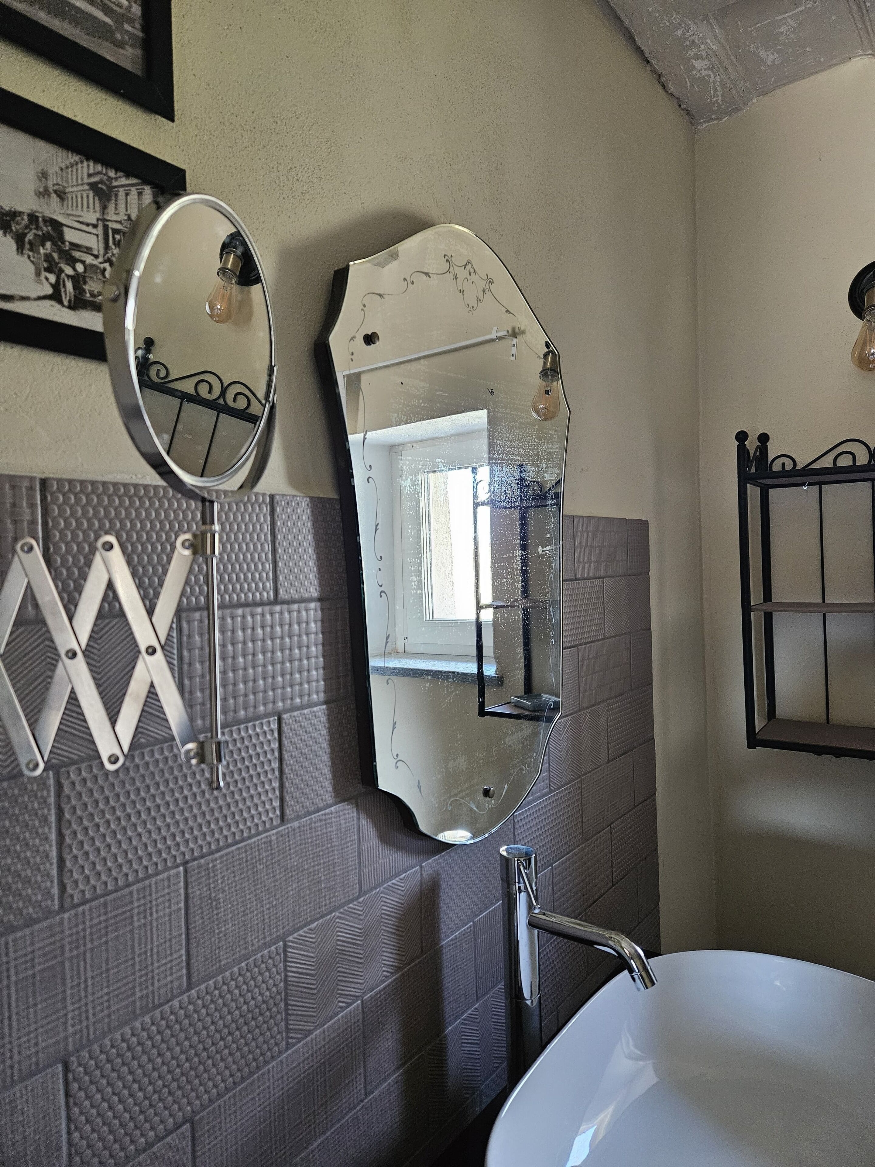 A bathroom with a large mirror, a sink, and a towel rack.